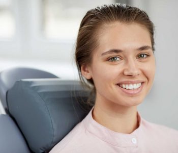 smiling-young-woman-in-dental-chair-38CBRJM