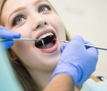 young-woman-sitting-dentist-s-chair-with-opened-mouth-dentist-s-office-while-having-examination_109285-1295
