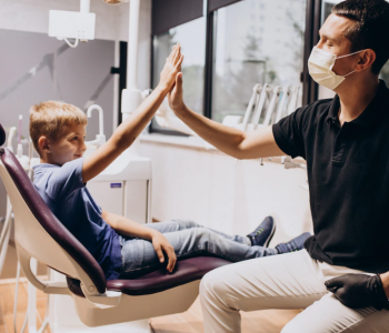 A doctor and a child in the dental clinic doing High Five